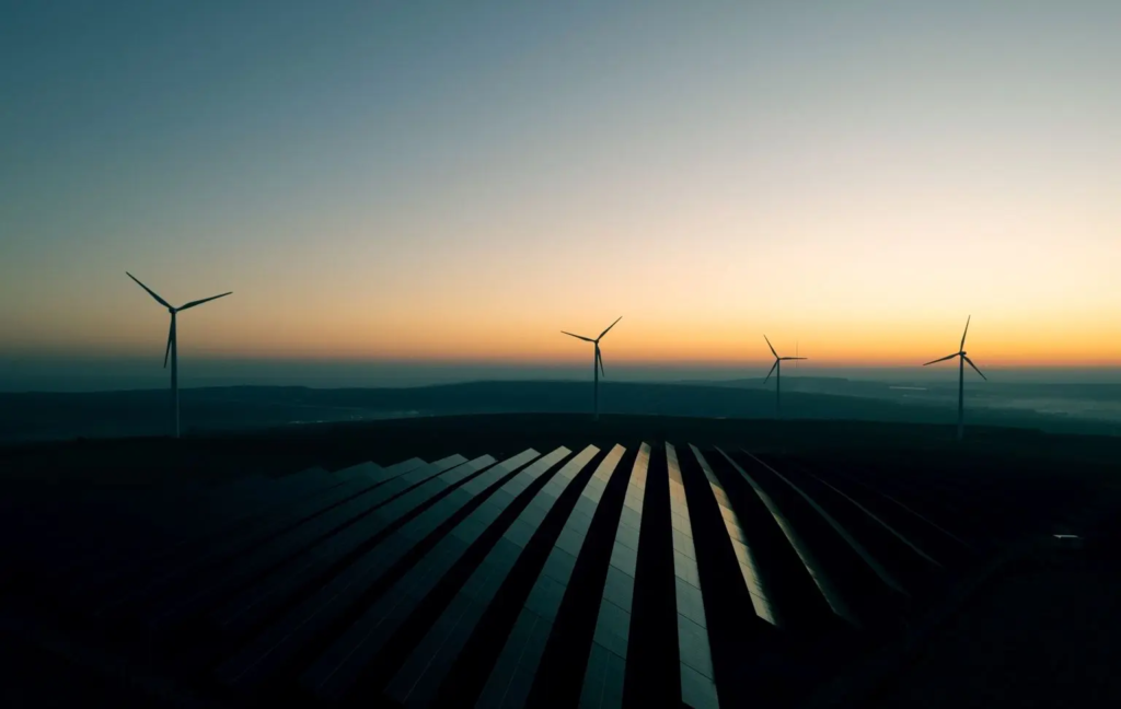 Eoliennes et panneaux solaire devant un coucher de soleil