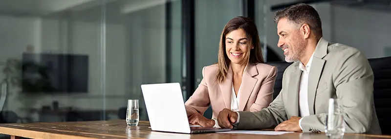 Une femme et un homme consultent des documents énergétiques sur un ordinateur portable