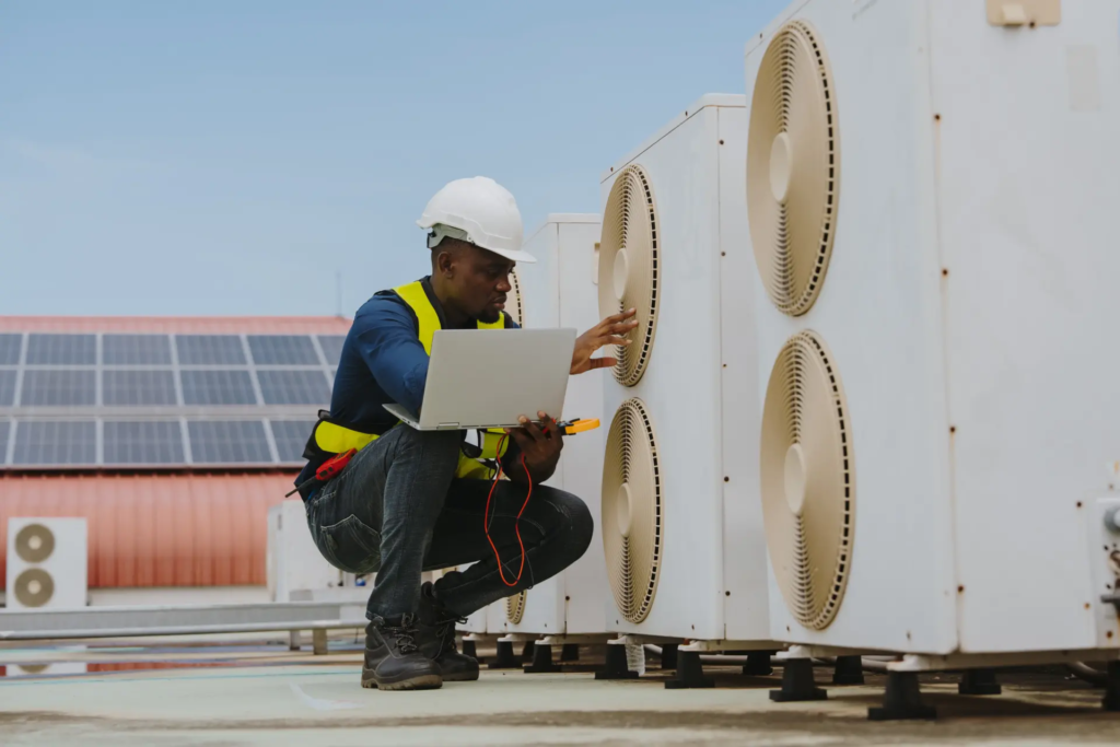 Technicien contrôlant des pompes à chaleur sur un bâtiment industriel, illustrant les bâtiments tertiaires soumis au décret BACS.