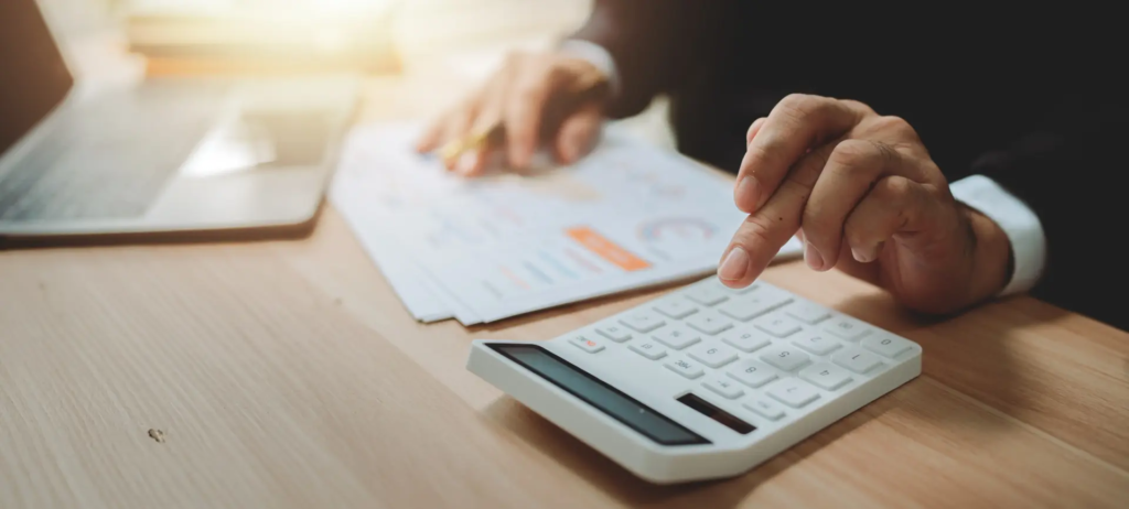 Calcul de données financières énergétiques sur une calculatrice avec documents et ordinateur