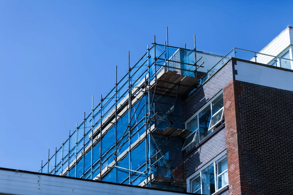 Bâtiment en briques en rénovation, à moitié recouvert d'échafaudages.