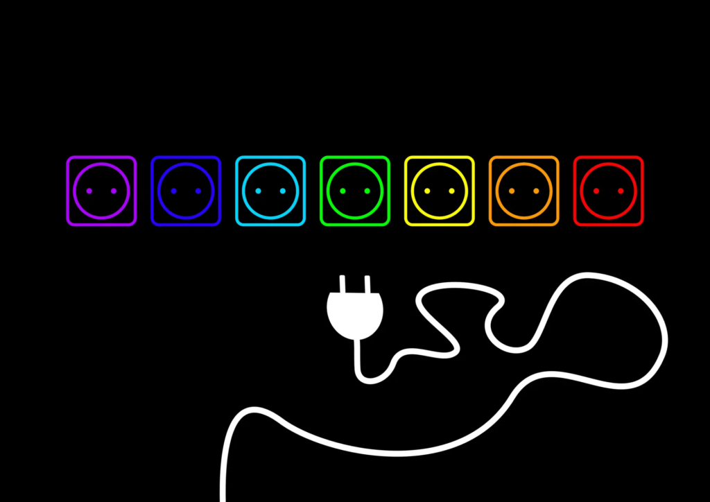 Une prise électrique mâle face à plusieurs prises femelles colorées, représentant le choix entre différentes offres d’électricité pour les professionnels.