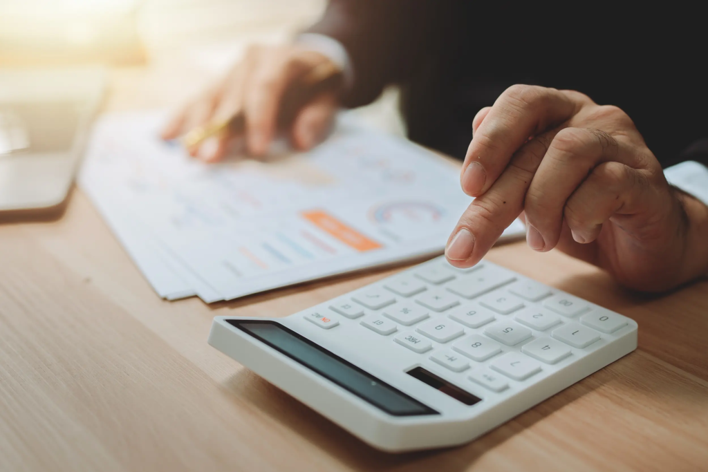 Calcul de données financières énergétiques sur une calculatrice avec documents et ordinateur