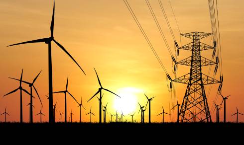 Pylônes électriques et éoliennes symbolisant la production et le transport d’énergie en France, en lien avec la CSPE 2026 et la fiscalité énergétique.