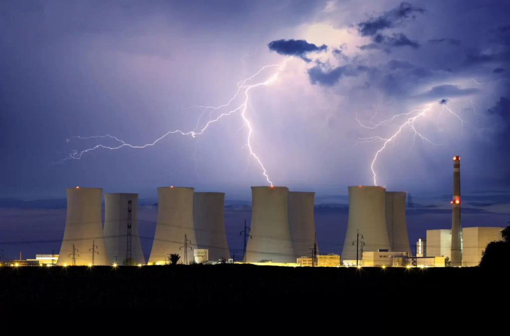 Centrale nucléaire éclairée de nuit avec des éclairs dans le ciel
