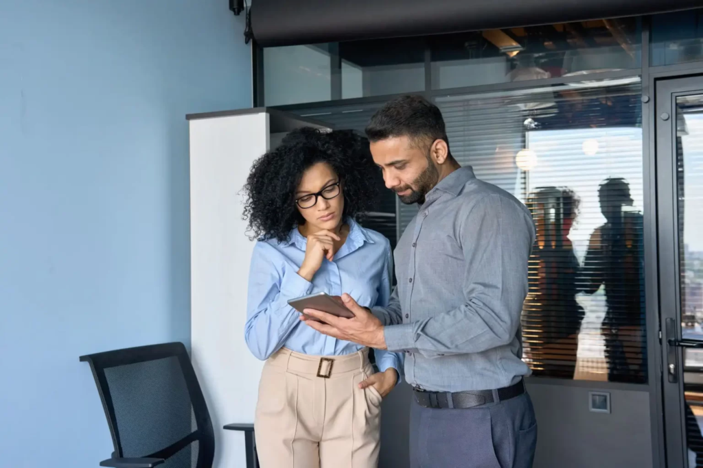 Une femme et un homme regardant un document sur une tablette.