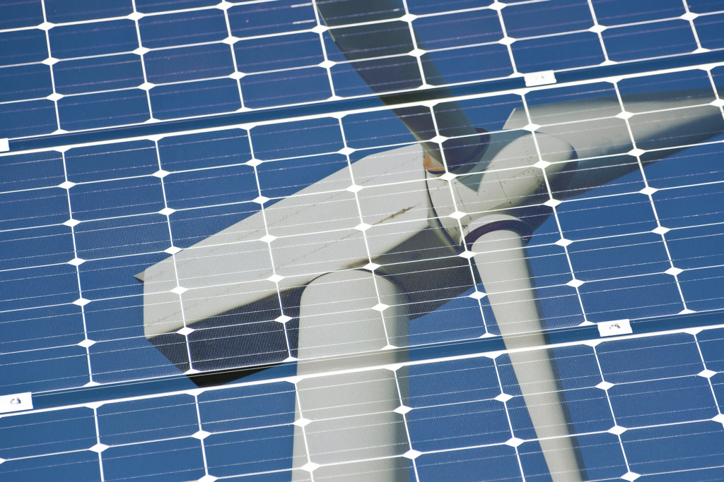 Reflet d’une éolienne dans un panneau photovoltaïque illustrant l’évolution du mix électrique européen