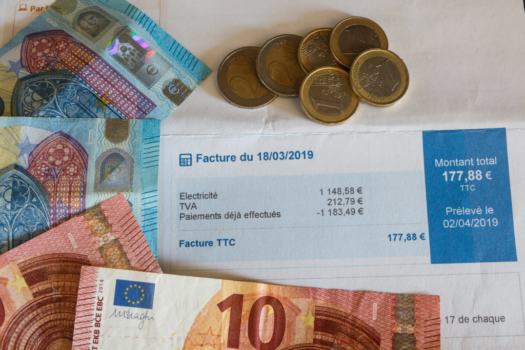 Facture d'électricité entourée de billets en euros pour illustrer le prix du mégawattheure d'énergie