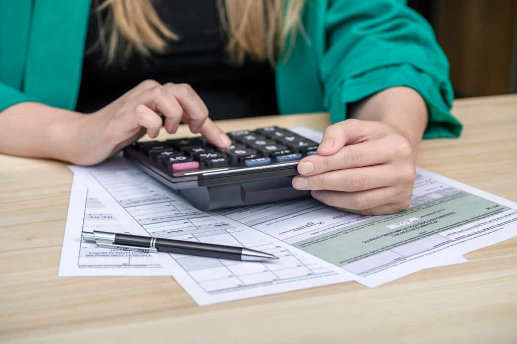 Personne examinant des formulaires fiscaux avec un stylo et une calculatrice pour préparer une demande de remboursement TICFE.