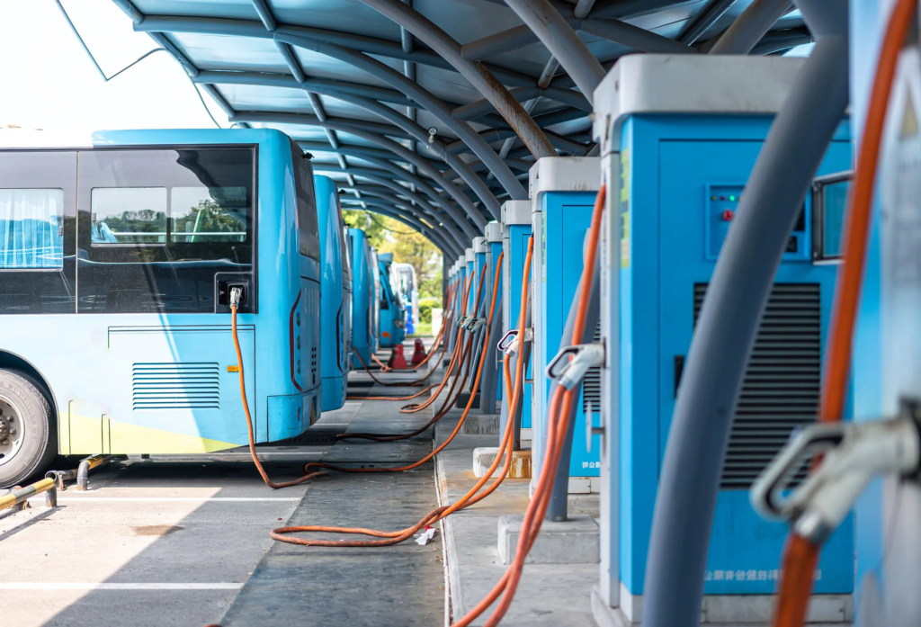 Bus électriques en charge sur une borne de recharge rapide, dans un dépôt de transport en commun équipé de plusieurs points de charge.