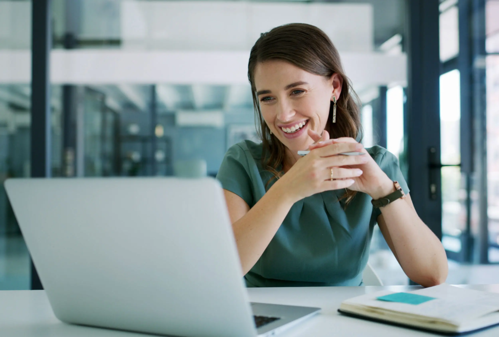 Femme souriant en regardant un écran d'ordinateur