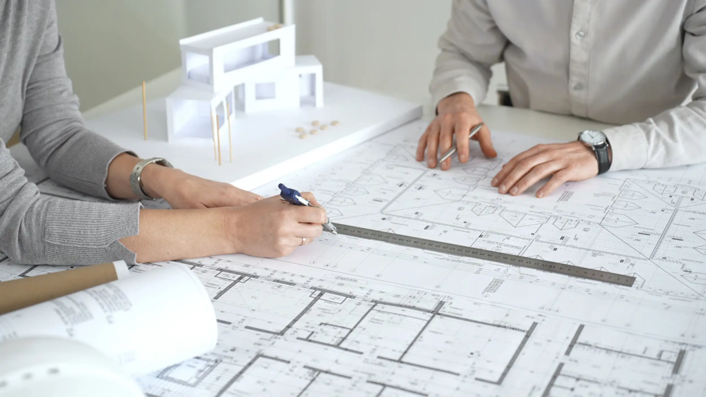 Deux personnes analysent un plan de bâtiment pour construire le plan de financement de travaux de rénovation
